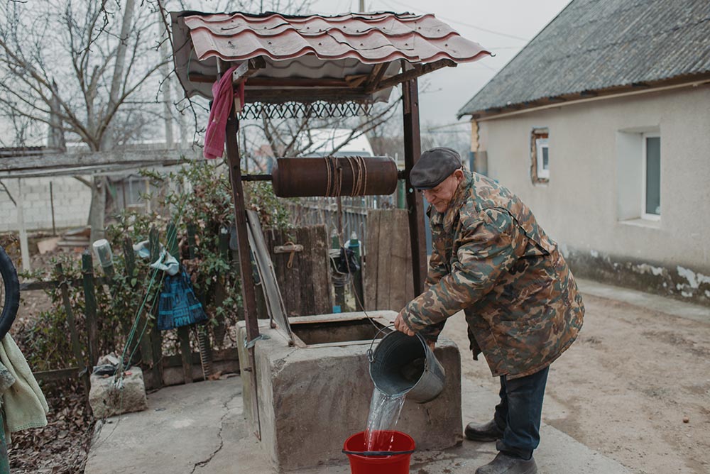 Mann schöpft Wasser aus Brunnen